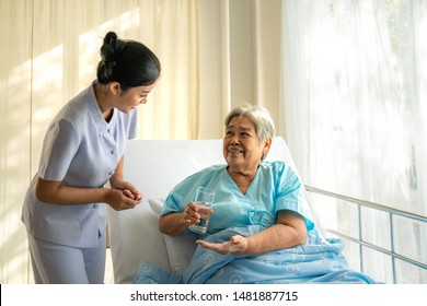 Asian nurse giving medication and glass of water to senior woman at hospital ward. Elderly patient care and health lifestyle, medical concept. - Powered by Shutterstock