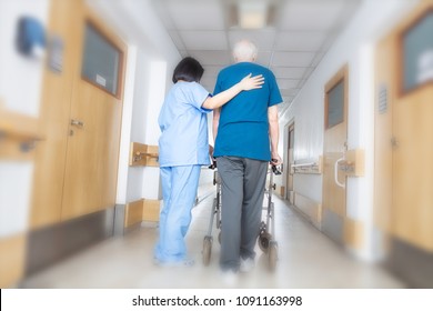 Asian nurse helping elder man walking in rehab facility.