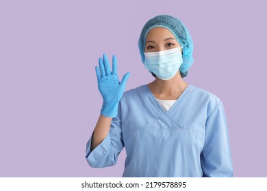 Asian Nurse In Medical Mask Waving Hand On Color Background