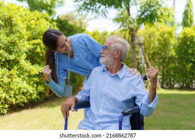 Asian Nurse Sitting On A Hospital Bed Next To An Older Man Helping Hands Care In Garden At Home. Elderly Patient Care And Health Lifestyle, Medical Concept.