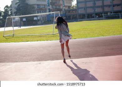 An Asian Office Lady Running Toward Sports Field Right After Work 