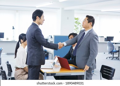 Asian office worker shaking their hands at the office - Shutterstock ID 1890489031