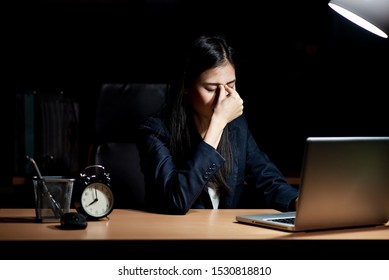 An Asian office worker is working overtime at the office. She has headache. - Shutterstock ID 1530818810