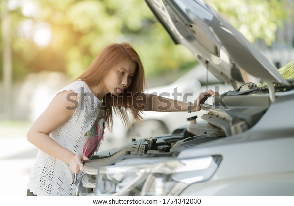 asian\
woman checking oil level in a car, change oil\
car\

