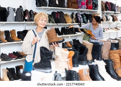 Asian And Old Caucasian Women Selecing New Shoes In Shop.