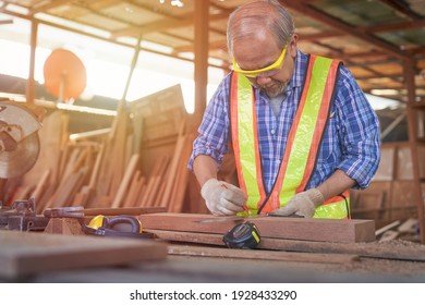 Asian Old Man Carpenter Work On Metering Wood Before Cutting For Furniture Building In Wooden Store