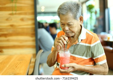 The Asian Old Man Drinking Strawberry Smoothie In The Restaurant. Selective Focus And Toned Image, Free Space For Text.