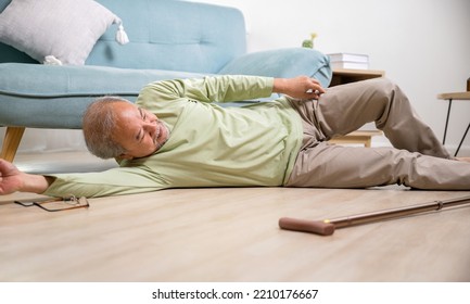 Asian Old Man Lying On Floor After Falling Down With Wooden Walking Stick, Sick Senior Man Beside Couch On Rug In Living Room At Home, Elderly Having An Accident After Doing Physical Therapy Alone