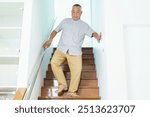 Asian old man slips on the wooden staircase while he has walking down the stair. Senior adult has an accident while walking on the stairway at home. Health care and wellbeing in senior people.