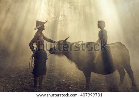 Asian old man standing and talking with girl riding buffalo over the ray of sun background, Countryside Lifestyle concept