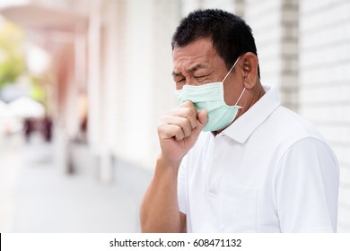 A Asian Old Man Wearing A Face Mask In The City Coughing