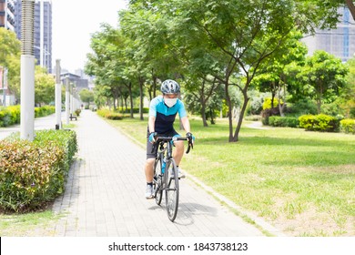 Asian old man wearing helmet and face mask is riding a bicycle in the park - enjoying sport or hobby living healthy - Powered by Shutterstock