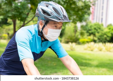 Asian old man wearing helmet and face mask is riding a bicycle in the park - enjoying sport or hobby living healthy - Powered by Shutterstock