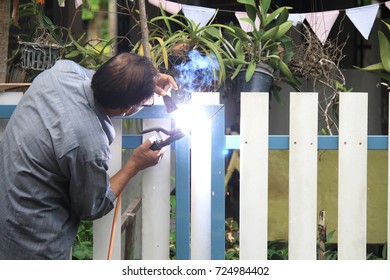 Asian Old Man Welding Steel For Home Fence.