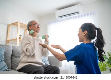 Asian Older Aged Man Doing Physiotherapist With Support From Nurse. Senior Elderly Male Sitting On Sofa In Living Room Using Dumbbells Workout Exercise For Patient With Caregiver In Nursing Care.