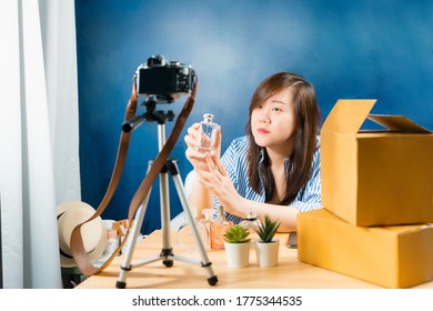 asian online seller woman talk and present with camera during vdo live and sell perfume to online shopping customer