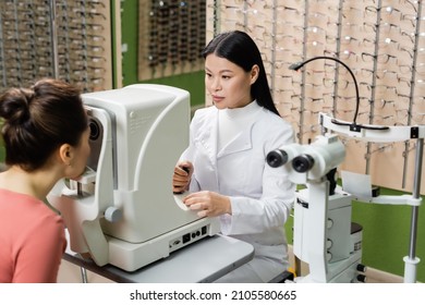 asian optometrist checking vision of blurred woman on ophthalmoscope in optics store