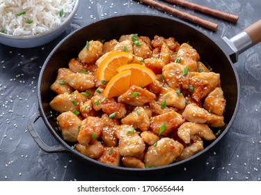 Asian Orange Chicken served in frying pan with fluffy white rice