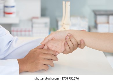 Asian Orthopaedic Doctor Doing Physical Examination In The Patient With Wrist Pain At The Clinic. Pain From Tendinitis And Sport Injury. Medical Concept