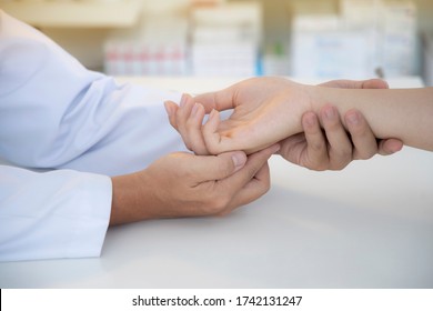 Asian Orthopaedic Doctor Doing Physical Examination In The Patient With Wrist Pain And Numbness At The Clinic. Selective Focus At Right Hand. Medical Concept.