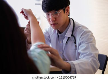 Asian Orthopedic Doctor Checking Patient 's Arm Bone In Hospital. The Sick Patient Having Orthopedic Disorder & Visit Doctor For Medical Treatment. Doctor Checking Reflex Action. Insurance Concept.