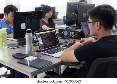 Asian Outsource Developer Team Sitting At Desk Working Laptop Computer Mobile Application Software Real Office