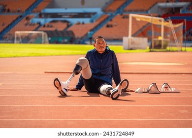 Asian para-athlete relaxes and Warm-up runner prosthetic leg on the track alone outside on a stadium track Paralympic running concept. - Powered by Shutterstock