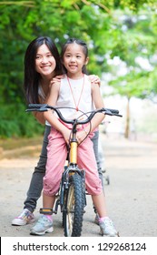 Asian Parent And Child Riding A Bike