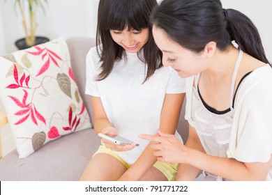 Asian Parent And Daughter With A Smartphone On Her Hand