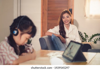 Asian Parent Mother Tutoring Watching Daughter Studying Online Class With Teacher Using Tablet Technology Video Call Conference, At Home Happy Smiling Parenthood Education Quarantine Covid-19 Pandemic