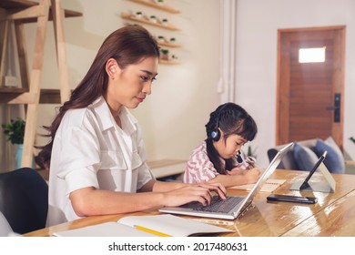 Asian Parent Mother Working At Home And Daughter Studying Online Class With Teacher Using Tablet Laptop Technology Video Call Conference, Happy Smiling Parenthood Education Quarantine Covid19 Pandemic