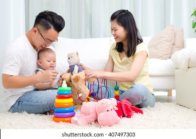 Asian Parent Playing With Their Baby In The Living Room