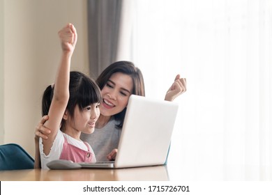 Asian Parent Teaching Homework To Children And Participate E-learning Online Education Class Group Activity From School Teacher At Home. Mother Explaining Knowledge In Computer Laptop To Daughter.