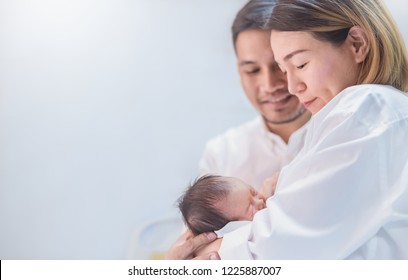 Asian Parents  Breastfeeding With Newborn Baby, Close Up Portrait Of Asian Young Couple Father And Mother Holding New Born Baby In Hospital. Happy Family Newborn Nursery Mother’s Day Holiday Concept