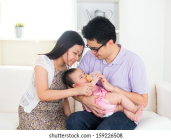 Asian Parents Feeding Baby Boy At Home