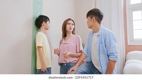 asian parents help their boy doing height measurement with worry about his shortness make them a bit depression
