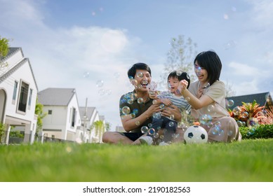 Asian parents and little boy enjoying during playing bubbles together in the park. Happy family life concept. - Powered by Shutterstock