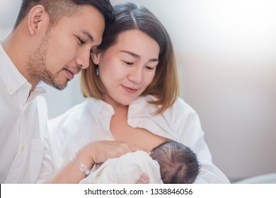 Asian Parents With Newborn Baby Being Breastfeeding, Portrait Of Asian Young Couple Father Mother Holding New Born Baby In Hospital Bed. Happy Family Love Breast Feeding Nursery Mother’s Day Concept 