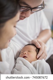 Asian Parents With Newborn Baby, Close Up Portrait Of Asian Young Couple Holding Their New Born Baby. Asian Father With His Hands Holding Baby Head.