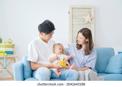 Asian parents sitting down on the sofa with their baby