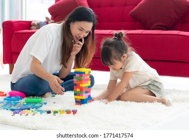asian parents teaching her kid to play puzzles at home. homeschooling and family together concept