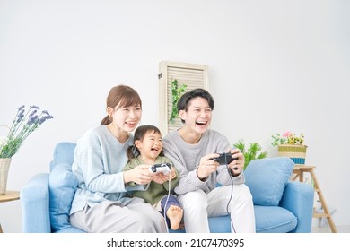 Asian Parents And Their Daughter Playing A Video Game At Home 