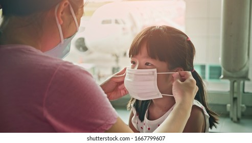 Asian Parents Wear Masks To Their Children Because Of Transmissible Infectious Diseases Indoor In The Airport