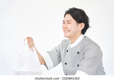 Asian Pastry Chef Passing A Plastic Bag In White Background