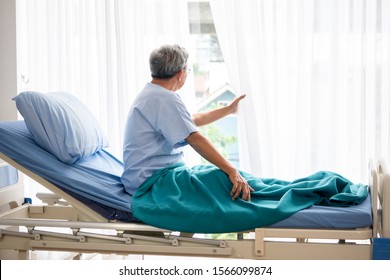 Asian Patient Man Looking Outside And Sitting On Hospital Bed In The Hospital Room.