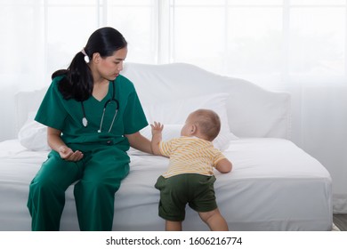 Asian pediatrician doctor woman green uniform hold stethoscope annual check up toddler boy by monitoring heart pulse rate , nurse play with preschool boy during examination, child health care concept - Powered by Shutterstock