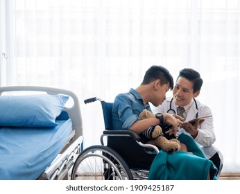 Asian pediatrician man check up diagnosis disability child patient on wheelchair for sickness recovery healing by smile and kindness emotional in hospital room - Powered by Shutterstock