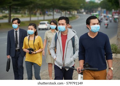 Asian People Of Different Ages Walking Along Street And Protected Themselves From Flue With Help Of Medical Masks