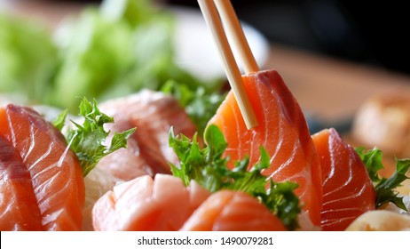 Asian people eating sashimi set in Asian restaurant. Hirame sashimi,salmon sashimi and tuna sashimi dish. Japanese food concept.