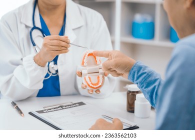 Asian people mature dentist having a compassionate conversation with elderly patient, discussing oral health results, providing expert advice and detailed dental report. Dental Guidance - Powered by Shutterstock